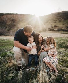 a man, woman and child are sitting in the grass with their arms around each other