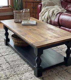 a wooden table sitting on top of a rug next to a leather couch in a living room