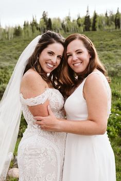 two women in wedding dresses hugging each other