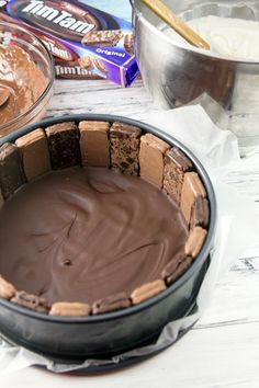 a cake pan with chocolate frosting in it on a table next to other baking supplies