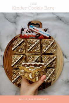 a person holding up a cookie bar on top of a wooden plate