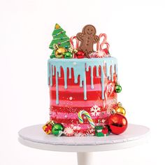 a decorated christmas cake sitting on top of a white table next to a red and blue frosted cake