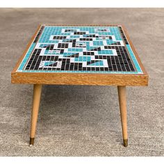 a small wooden table with blue and black tiles on it's top, sitting on the floor