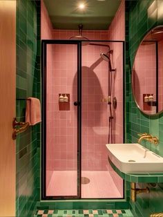 a bathroom with green and pink tiles on the walls, sink, shower stall and mirror