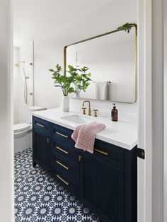 a bathroom with blue and white tile flooring and gold accents on the mirror above the sink