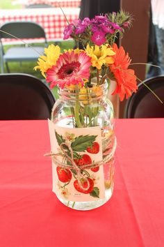 a vase filled with flowers sitting on top of a red tablecloth covered dining room