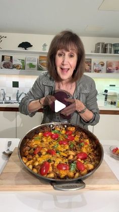 a woman standing in front of a pan filled with food