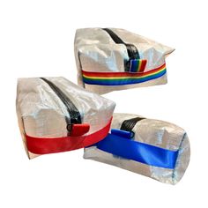 two white bags with blue, red, and yellow ribbons on each bag are sitting side by side