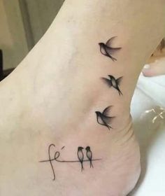 a small tattoo on the foot of a woman with birds flying above her head and two letters