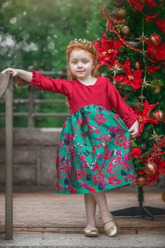 OUR DESIGN - THE CRISTINA DRESS An asymmetrical hem and a bold color contrast make this amazing Holiday dress a must-have for anybody looking to add some elegance this season. The long sleeves and ruffled, embroidered cuffs are certain to make your little girl feel like a real-life princess wherever she goes with this beautiful Christmas dress.  ●Three-quarter sleeves ●Ruffled cuffs with embroidery detail ●Asymmetrical hem ●High neckline ●Soft fabric ●Floral embroidered bottom ●Rear button fastening ●Tailored to your little one's measurements ●The listing is for the Cristina dress only OUR PROMISE We only use the highest quality fabrics to handmade unique and memorable pieces for your little one. We design and create this piece with love and with attention to detailed. *Please refer to our Green Dress For Christmas, Green Winter Dresses, Red And Green Dress, Girls Winter Dress, Floral Dress Winter, White Baptism Dress, Embroidered Cuffs, Real Life Princesses, Girls Winter Dresses