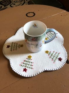 a cup and saucer sitting on top of a table with a white doily