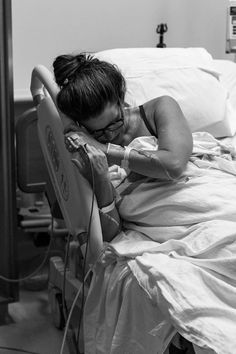 a woman laying in a hospital bed with her head resting on the armrests