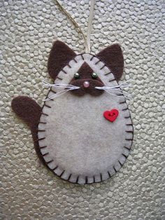 a cat ornament hanging on a wall with a heart in the middle and eyes