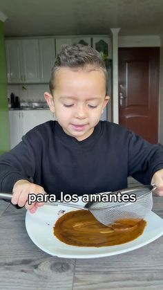 a young boy sitting at a table with a plate of food in front of him