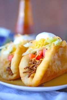 two tacos sitting on top of a white plate next to a blue and yellow napkin