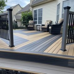 a deck with chairs and railings in front of a house