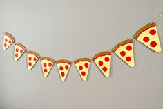 a paper garland with red polka dot pizza slices hanging from it's sides on a gray wall