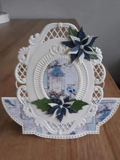 a white card with blue and green flowers on it sitting on top of a wooden table