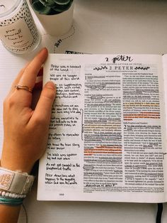 a person is holding an open bible on a table