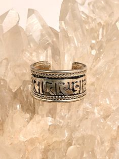 This adjustable ring is hand crafted by local artists of Katmandu Nepal. It features the well known and beloved Tibetan holy mantra Om Mani Padme Hum artfully carved around the band, with a delicate ropelike design around both sides. The ring can be gently pressed together to adjust to whichever finger on which you choose to wear it. Wear it for protection in all directions and to bring love and spiritual harmony into your journey. Made of sterling silver, it is attractive and adjustable. Measur Adjustable Symbolic Carved Rings, Adjustable Spiritual Sterling Silver Engraved Ring, Symbolic Adjustable Promise Jewelry, Spiritual Promise Engraved Ring, Spiritual Engraved Promise Ring, Spiritual Open Ring Jewelry For Ceremonial Occasion, Ceremonial Spiritual Engraved Ring With Intricate Design, Ceremonial Spiritual Style Open Ring Jewelry, Adjustable Spiritual Etched Jewelry