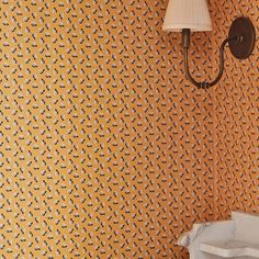 a wall with a lamp on it next to a white toilet and yellow wall paper