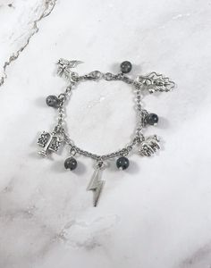 a bracelet with charms on it sitting on top of a marble countertop next to a silver chain