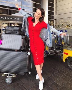 a woman in a red dress is standing next to luggage