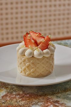 a white plate topped with a cake covered in frosting and strawberries on top of it