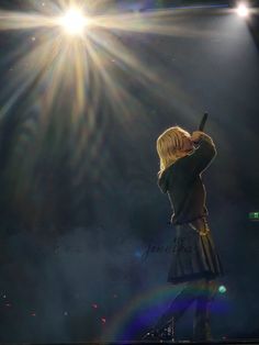 a woman standing on top of a stage holding a microphone in her hand and looking up at the sky