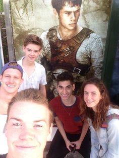 a group of young people standing next to each other in front of a movie poster