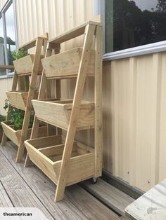 several wooden planters sitting on the side of a building with plants growing in them