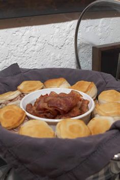 some pancakes and bacon in a bowl on top of a table with other food items