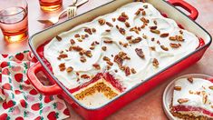 a red casserole dish with white frosting and pecans