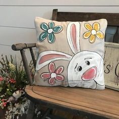 a decorative pillow with an image of a bunny and flowers on it sitting on a chair