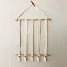 a white wall hanging with four wooden pegs