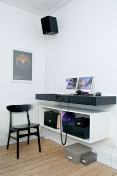 a room with a desk, chair and pictures on the wall above it that is connected to two speakers