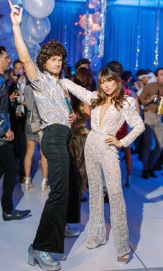 a man standing next to a woman on top of a dance floor with balloons in the air