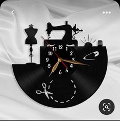 a clock that is on the side of a white sheet with scissors and sewing machine