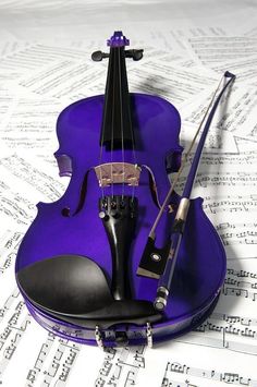 a purple violin sitting on top of sheet music