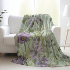 a white couch sitting next to a window covered in a green and purple flowered blanket