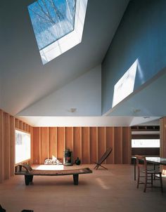 an empty room with wooden paneling and skylights above the table, in front of two windows