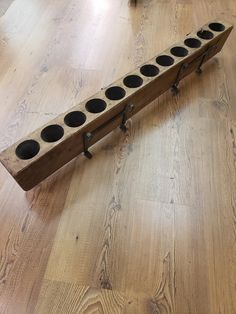 a wooden pipe holder with six holes on the top and two legs, sitting on a wood floor