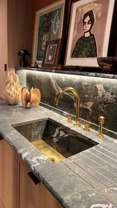 a kitchen with marble counter tops and gold faucets on the sink's edge