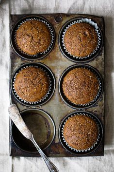 four muffins in a metal pan with a spoon