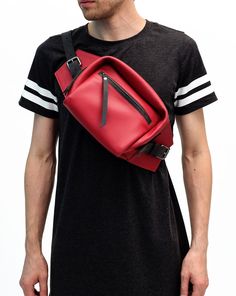 a man wearing a black and white t - shirt is holding a red bag