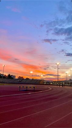 the sun is setting over an empty track