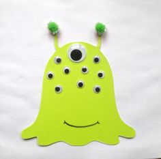 a green paper cut out with googly eyes