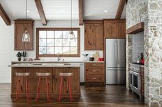 a kitchen with wooden cabinets and stools next to an island in front of a window