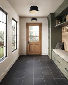 a hallway with black tile flooring and wooden door