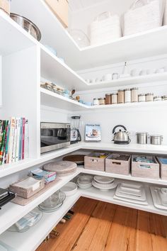 a kitchen with white cabinets and shelves filled with dishes, pans and utensils